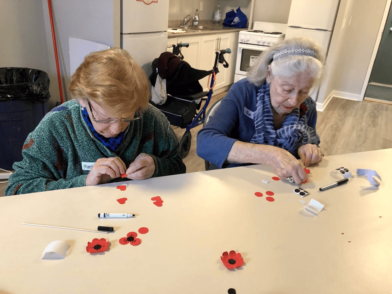 Two participants crafting paper poppies at a table